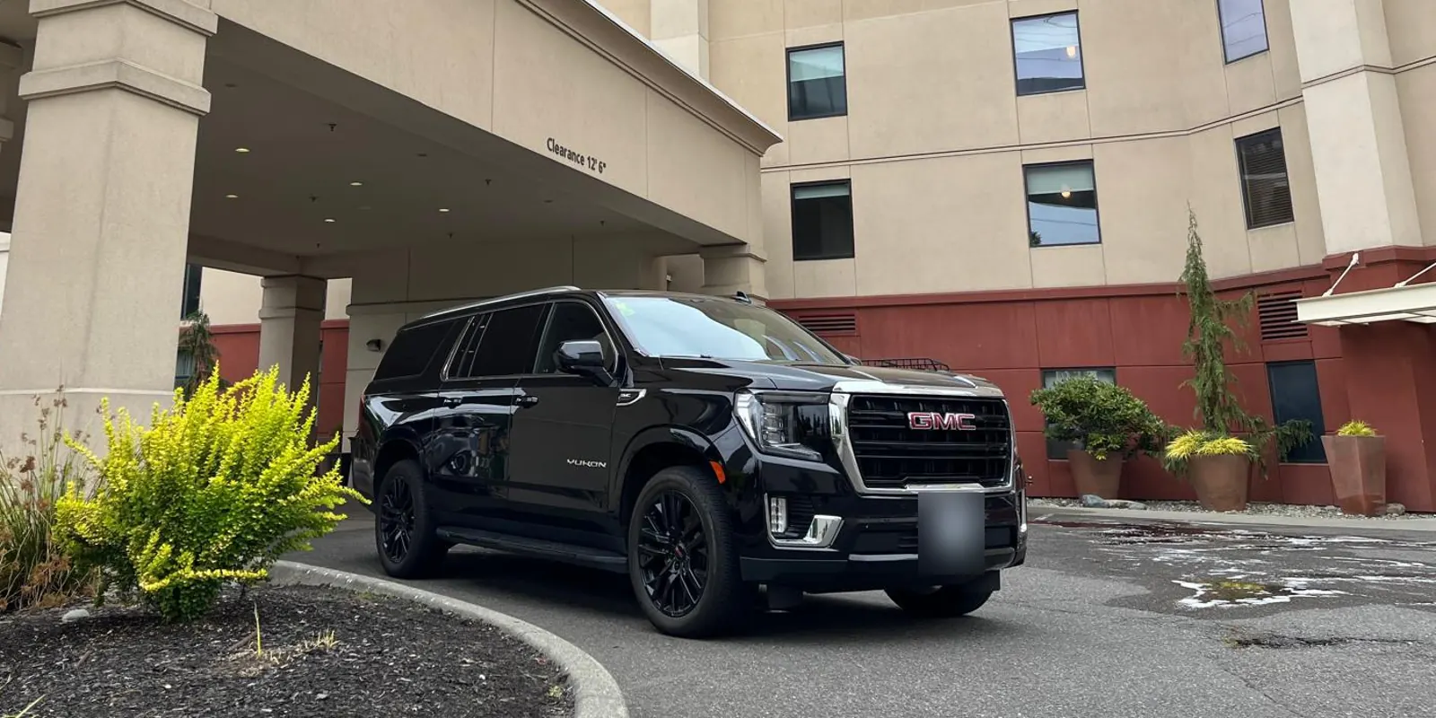 Black GMC Yukon XL parked under a hotel's covered entrance