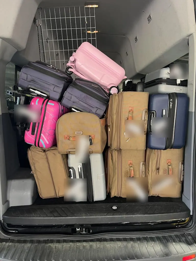 Suitcases loaded into the back of a passenger van